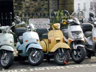 Another street scene. Trendy Londoners ride scooters.